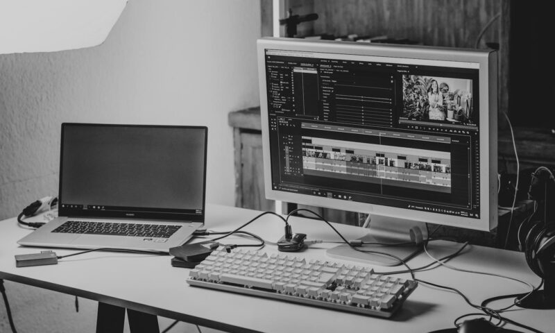 A monochrome workspace setup featuring a laptop and monitor for video editing.